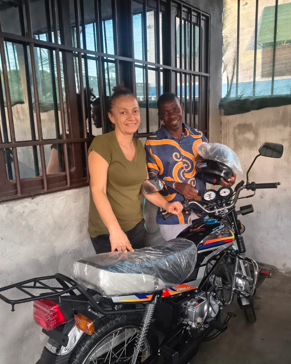 Presbyter Daniel with the motorcycle he received to work as a motorcycle taxi driver